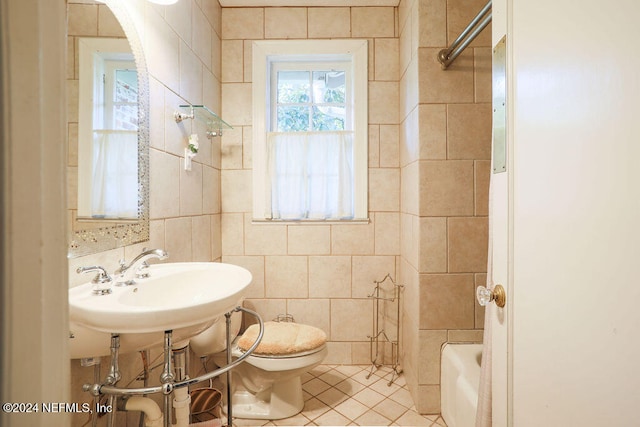 full bathroom with toilet, tile patterned flooring, sink, tiled shower / bath combo, and tile walls