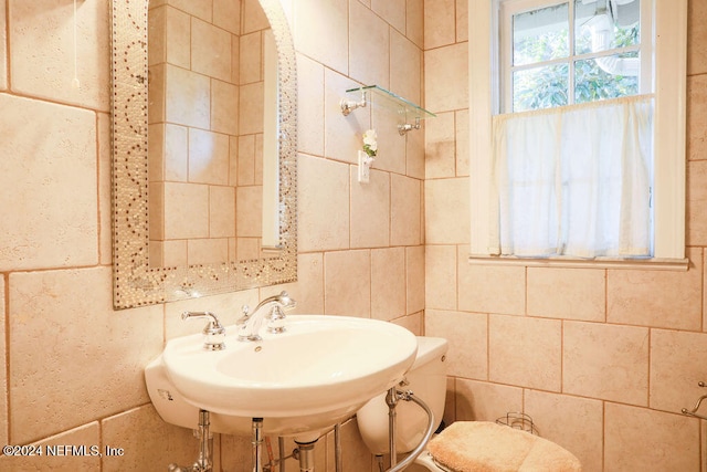 bathroom featuring toilet, tile walls, and sink