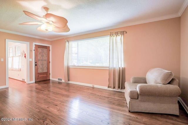 sitting room with crown molding, wood-type flooring, a textured ceiling, and ceiling fan