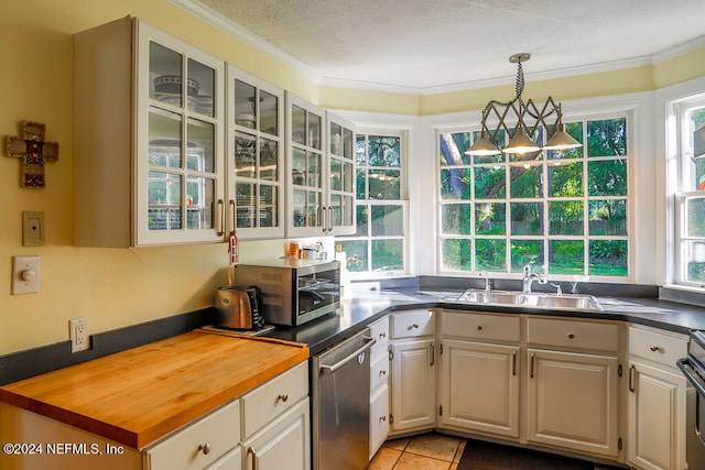 kitchen with sink, butcher block counters, a textured ceiling, hanging light fixtures, and crown molding