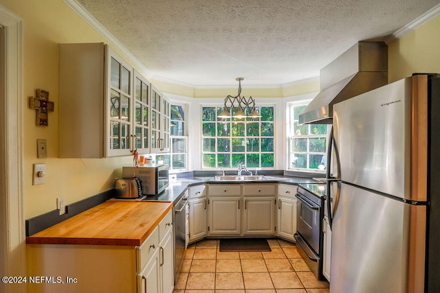 kitchen with wooden counters, pendant lighting, crown molding, and stainless steel appliances