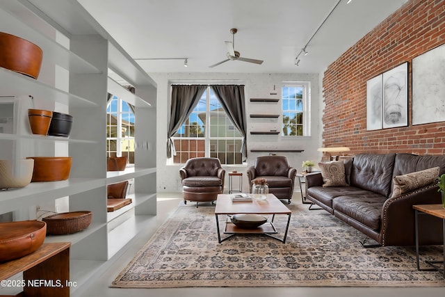 living room featuring plenty of natural light, rail lighting, and brick wall