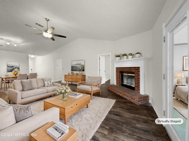 living room with lofted ceiling, ceiling fan, a textured ceiling, dark hardwood / wood-style floors, and a fireplace