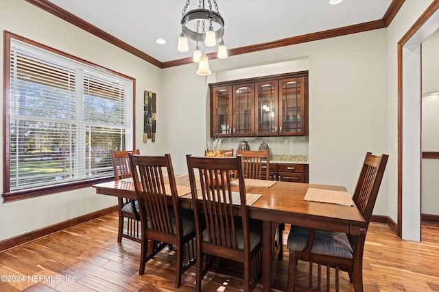 dining room with a notable chandelier, light wood-type flooring, and ornamental molding