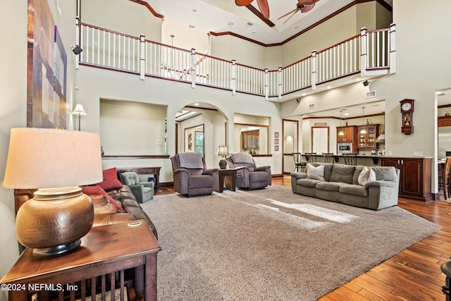 living room with wood-type flooring, a towering ceiling, and ceiling fan