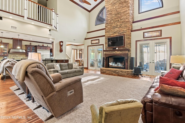 living room with french doors, ornamental molding, high vaulted ceiling, a fireplace, and hardwood / wood-style floors