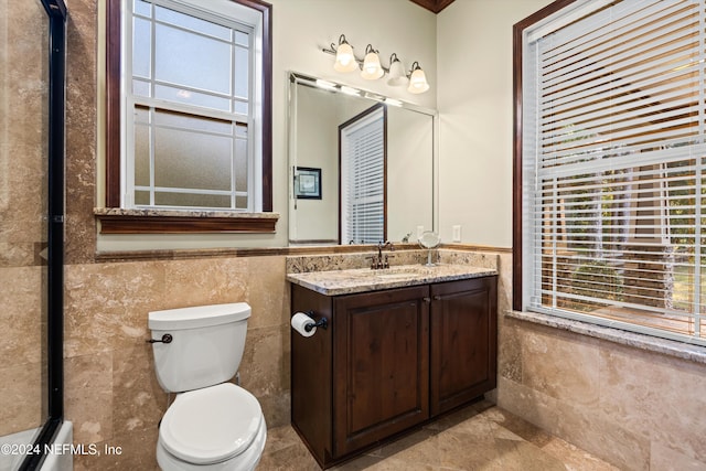 bathroom with a wealth of natural light, vanity, and tile walls