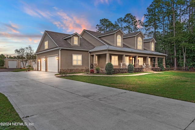 view of front of home featuring a garage, covered porch, and a yard