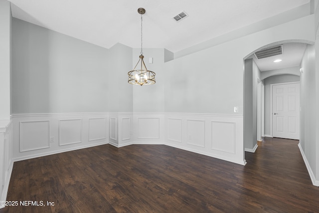 spare room featuring dark hardwood / wood-style flooring and a chandelier