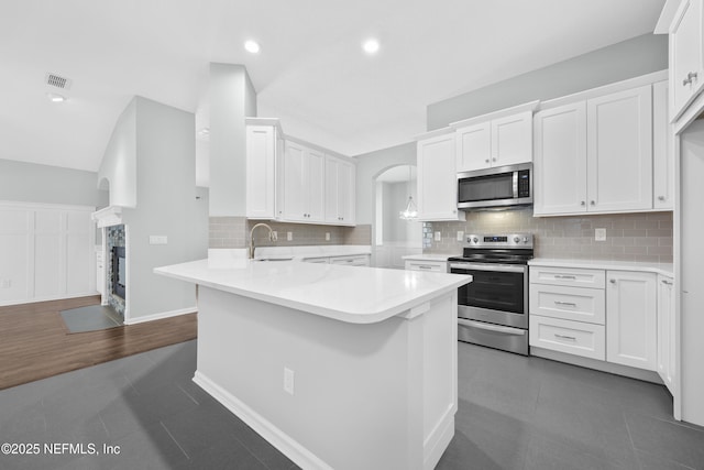 kitchen with kitchen peninsula, stainless steel appliances, white cabinetry, and sink