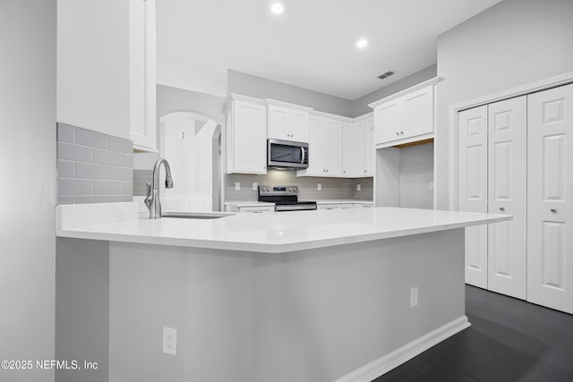 kitchen with sink, white cabinets, appliances with stainless steel finishes, and kitchen peninsula