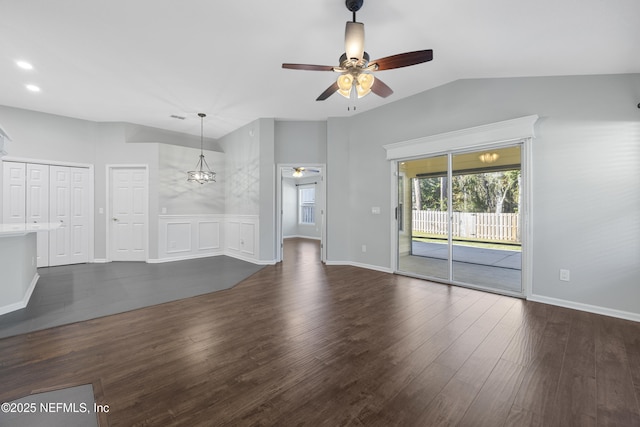 unfurnished living room featuring vaulted ceiling, dark hardwood / wood-style floors, and ceiling fan with notable chandelier