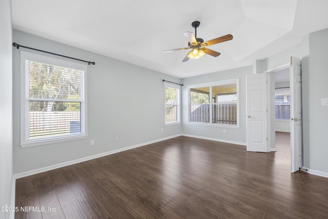 spare room with dark hardwood / wood-style floors, a raised ceiling, and ceiling fan