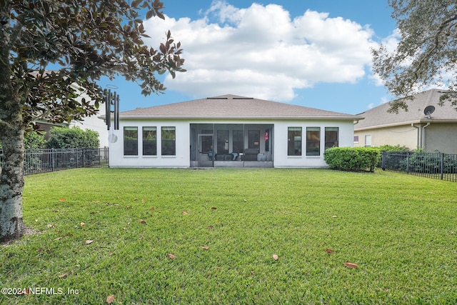 rear view of house featuring a lawn and a sunroom