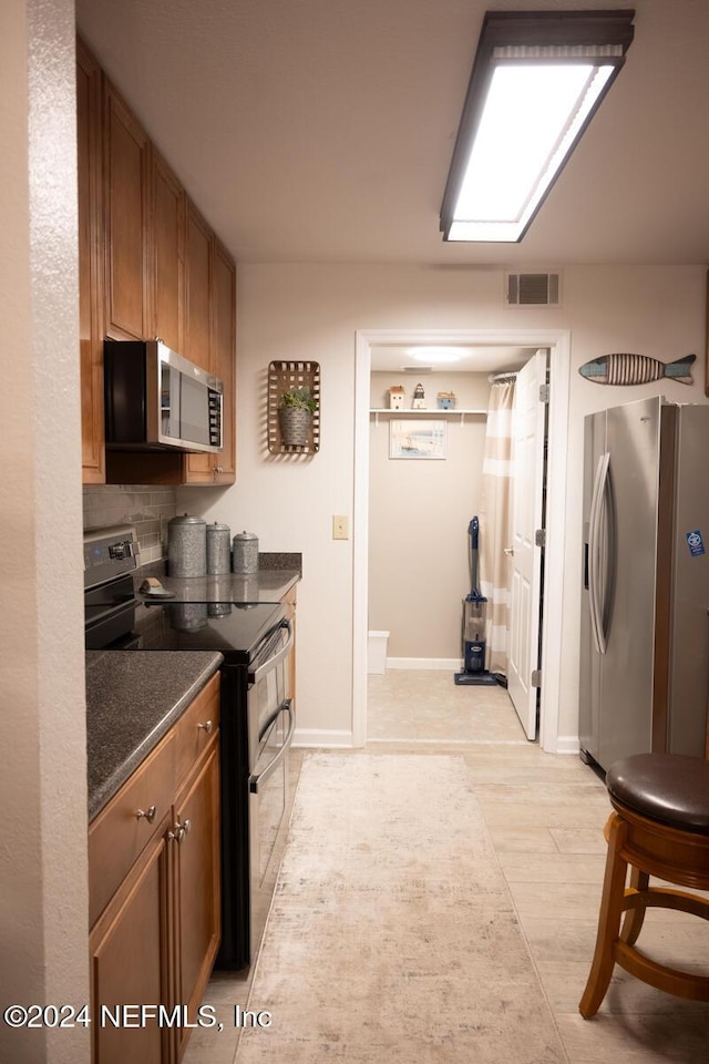 21 Arbor Club Dr Unit 101, Ponte Vedra Beach, FL 32082 - kitchen with baseboards, stainless steel appliances, brown cabinets, and visible vents