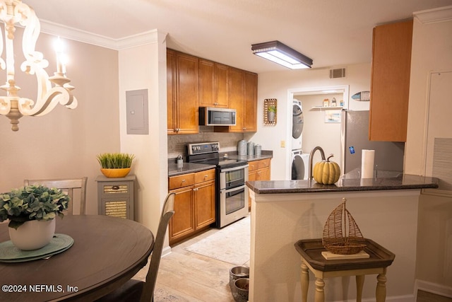 21 Arbor Club Dr Unit 101, Ponte Vedra Beach, FL 32082 - kitchen featuring visible vents, stacked washer and dryer, brown cabinets, appliances with stainless steel finishes, and backsplash
