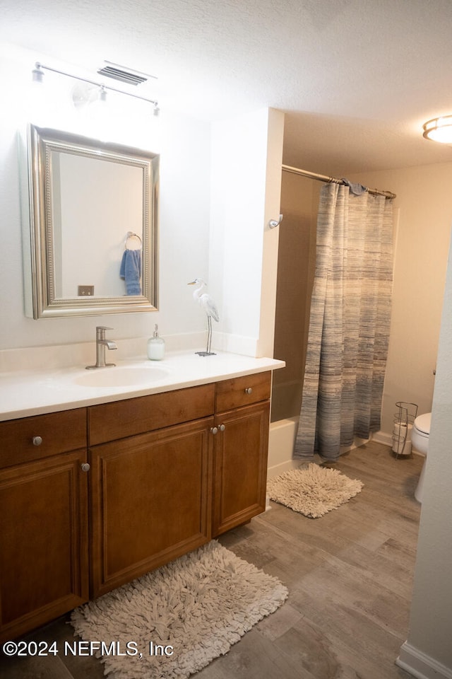 full bathroom featuring vanity, shower / tub combo, hardwood / wood-style flooring, and toilet