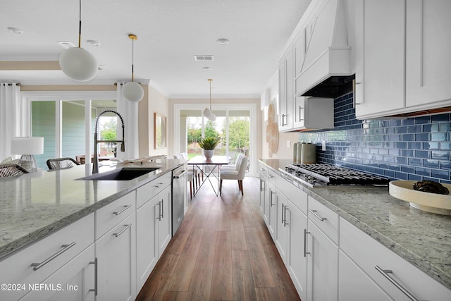 kitchen featuring dark hardwood / wood-style floors, custom range hood, hanging light fixtures, white cabinetry, and light stone counters