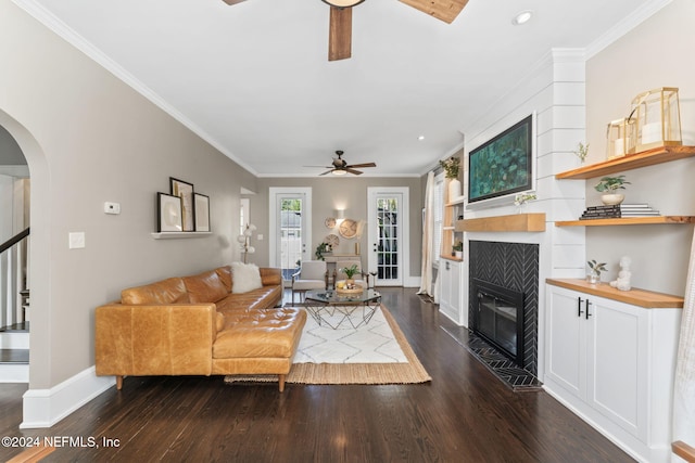 living room featuring a fireplace, dark hardwood / wood-style flooring, ceiling fan, and crown molding