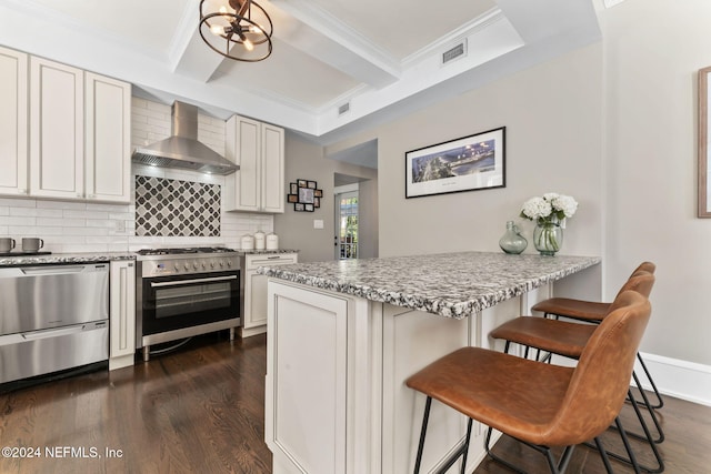 kitchen featuring white cabinetry, appliances with stainless steel finishes, a kitchen bar, dark wood-type flooring, and wall chimney exhaust hood