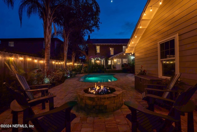 patio at twilight featuring a fenced in pool and an outdoor fire pit