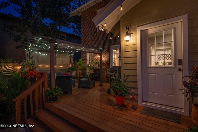 deck at night featuring a grill and a pergola