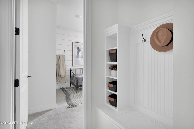 hallway with crown molding and light carpet