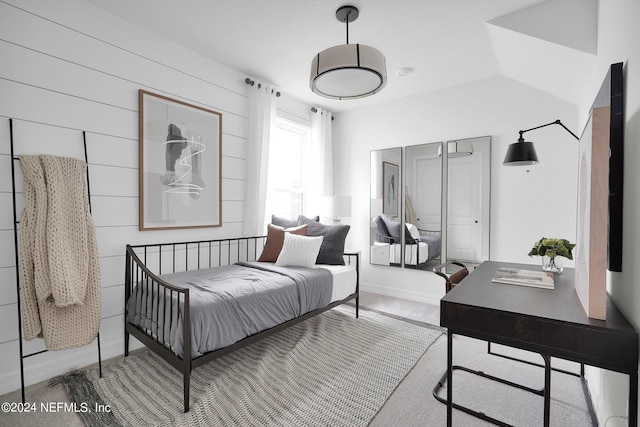 bedroom featuring vaulted ceiling and wood walls