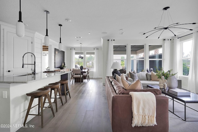 living room featuring sink, a notable chandelier, a textured ceiling, and light hardwood / wood-style floors