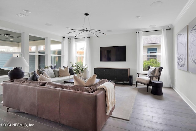 living room with ornamental molding, a notable chandelier, hardwood / wood-style floors, and a wealth of natural light