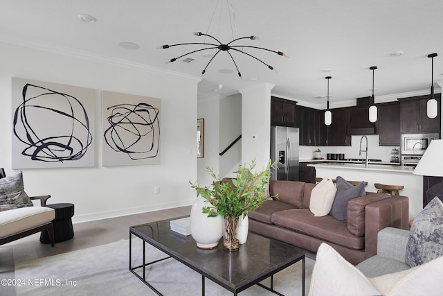 living room with light tile patterned floors, decorative columns, ornamental molding, a notable chandelier, and sink