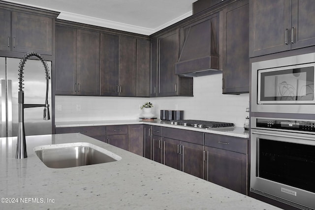 kitchen featuring built in appliances, light stone counters, dark brown cabinetry, and custom range hood