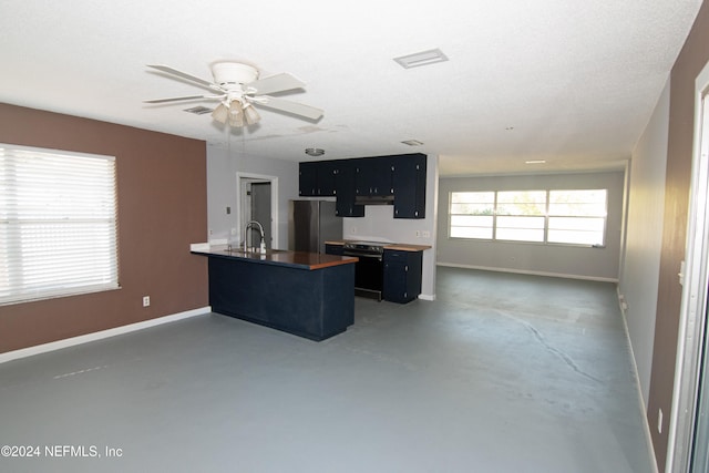 kitchen with a kitchen breakfast bar, kitchen peninsula, ceiling fan, black oven, and stainless steel fridge