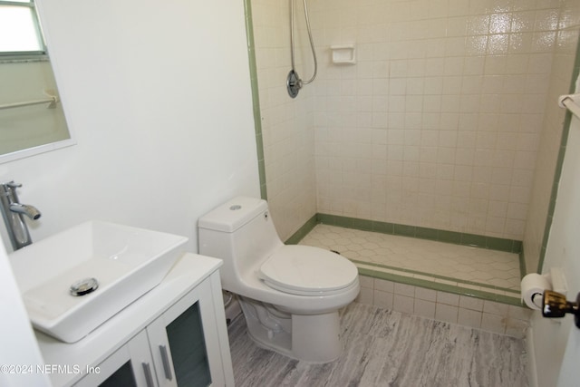 bathroom with a tile shower, hardwood / wood-style flooring, vanity, and toilet