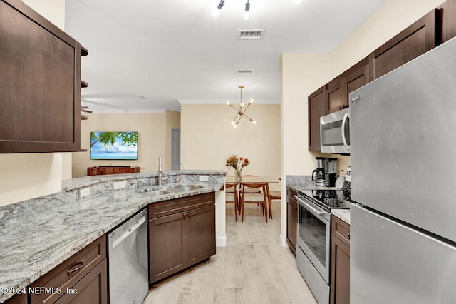 kitchen with kitchen peninsula, appliances with stainless steel finishes, light stone countertops, ornamental molding, and light hardwood / wood-style floors