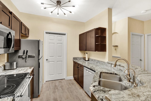 kitchen with sink, an inviting chandelier, light wood-type flooring, appliances with stainless steel finishes, and light stone counters