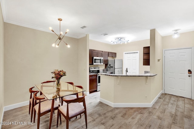 kitchen with a kitchen breakfast bar, light hardwood / wood-style flooring, kitchen peninsula, stainless steel appliances, and a chandelier