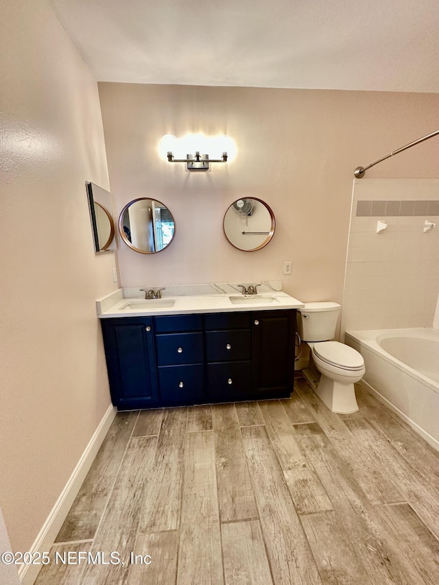 bathroom featuring double vanity, a sink, toilet, and wood finished floors