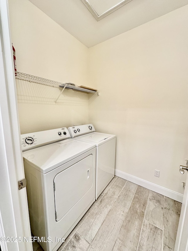 washroom featuring light wood-type flooring, washing machine and dryer, laundry area, and baseboards