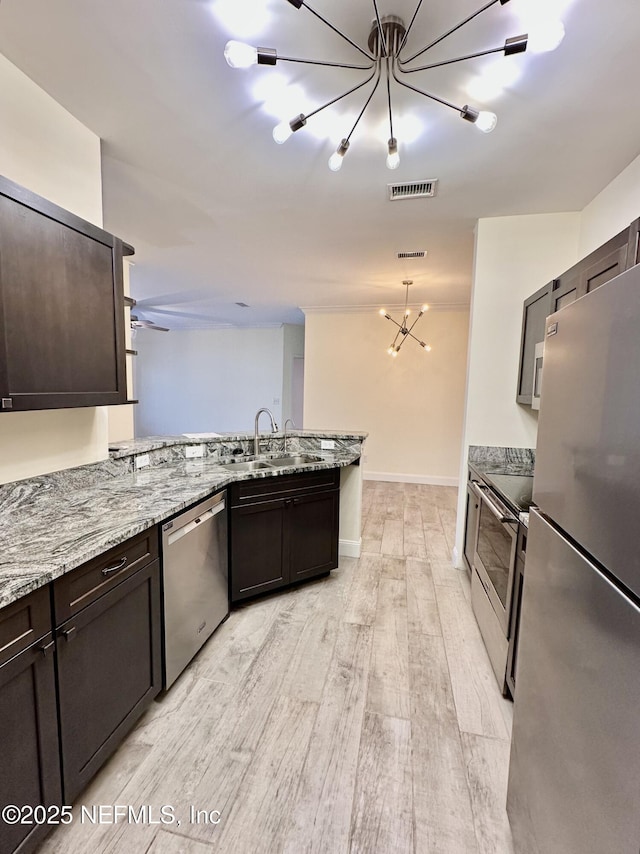 kitchen with visible vents, light wood-style flooring, appliances with stainless steel finishes, a sink, and a peninsula