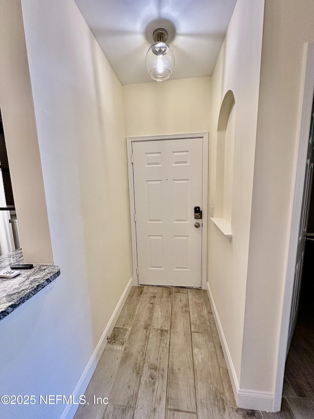 doorway with baseboards and light wood-style floors