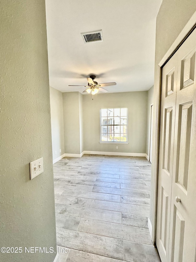 spare room featuring ceiling fan, wood finished floors, visible vents, and baseboards