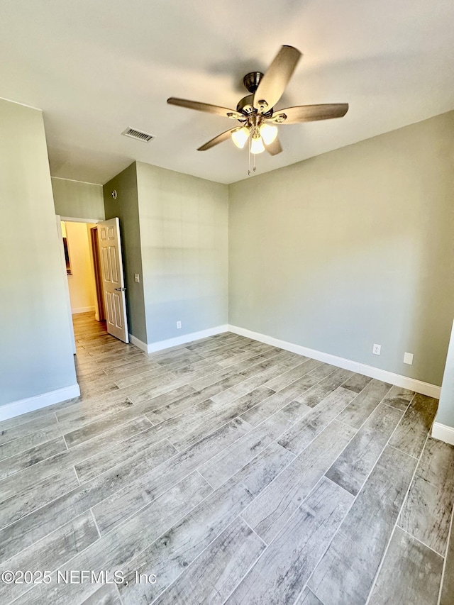 empty room featuring ceiling fan, wood finished floors, visible vents, and baseboards