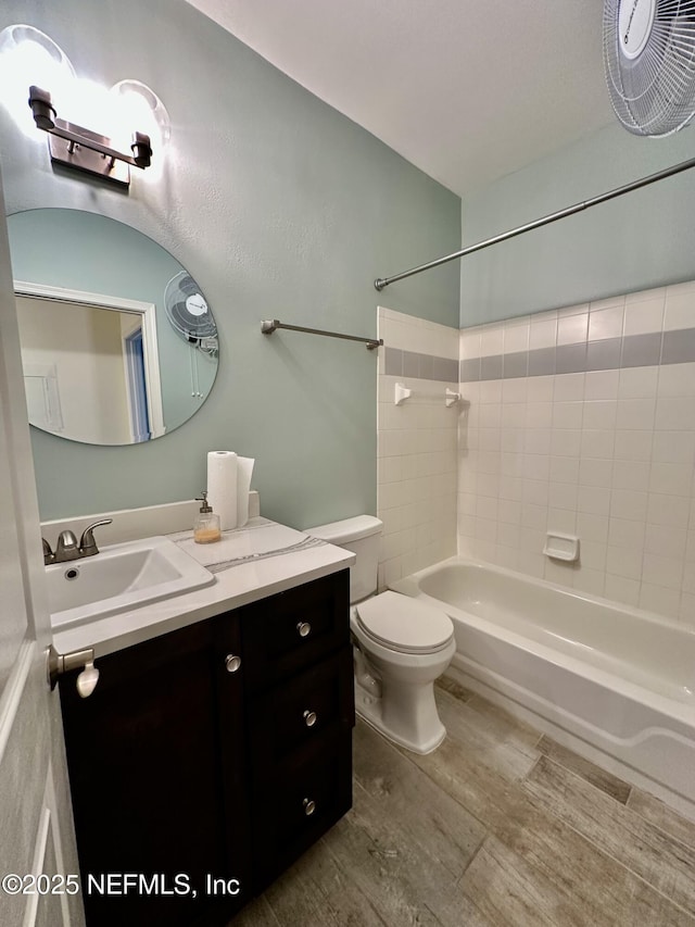 bathroom featuring toilet, vanity, wood finished floors, and shower / bathtub combination