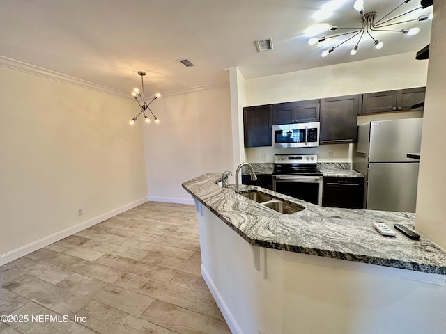 kitchen featuring stone countertops, visible vents, appliances with stainless steel finishes, an inviting chandelier, and a sink