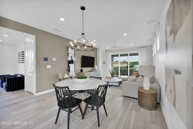 dining area with ceiling fan with notable chandelier and light hardwood / wood-style floors