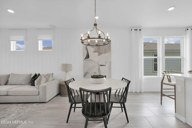 dining space featuring wooden walls, a notable chandelier, and plenty of natural light