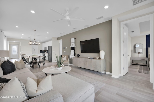 living room featuring light hardwood / wood-style floors and ceiling fan with notable chandelier