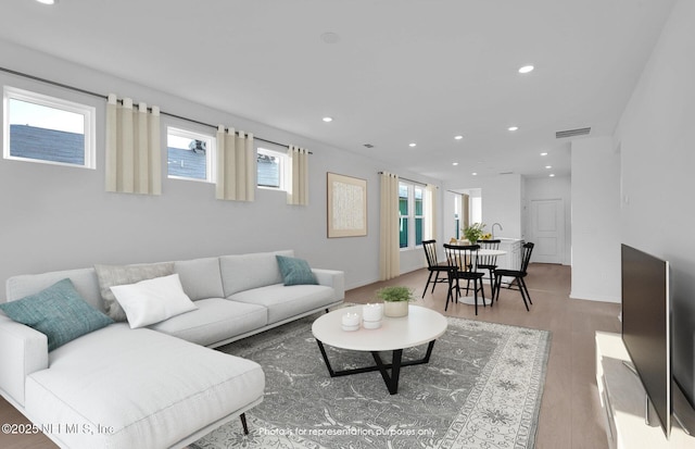 living area with recessed lighting, wood finished floors, visible vents, and baseboards