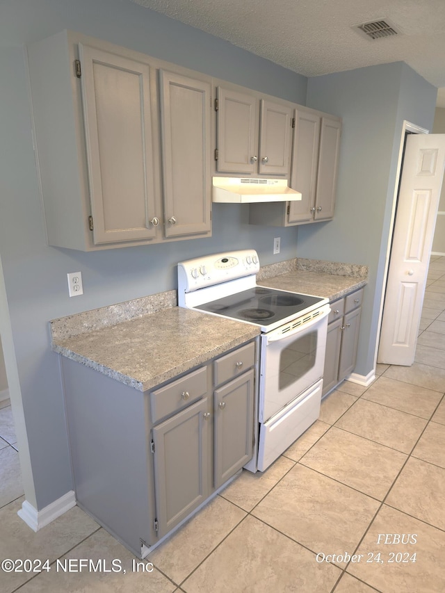 kitchen featuring light tile patterned floors, a textured ceiling, electric range, and gray cabinets